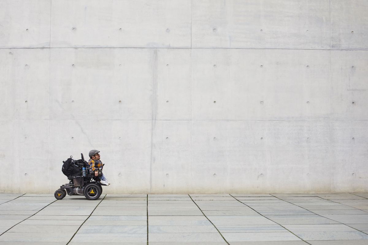Raúl Krauthausen fährt vor einer hohen Betonwand über große Betonplatten. 
