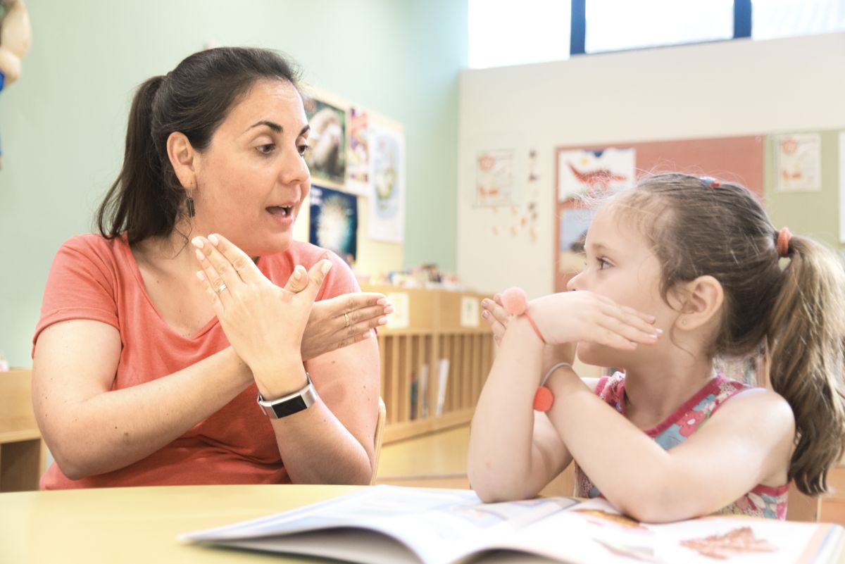 Eine Gebärdensprachlehrerin und ihre Schülerin üben eine Gebärde der amerikanischen Gebärdensprache.  
